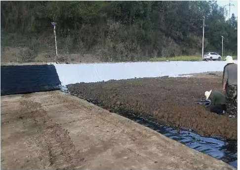 Black lining sheet being laid along the edge of a farm reservoir.