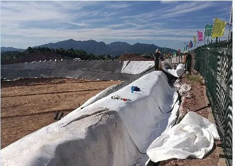 A landfill cell with lining being installed across the base and side slope.